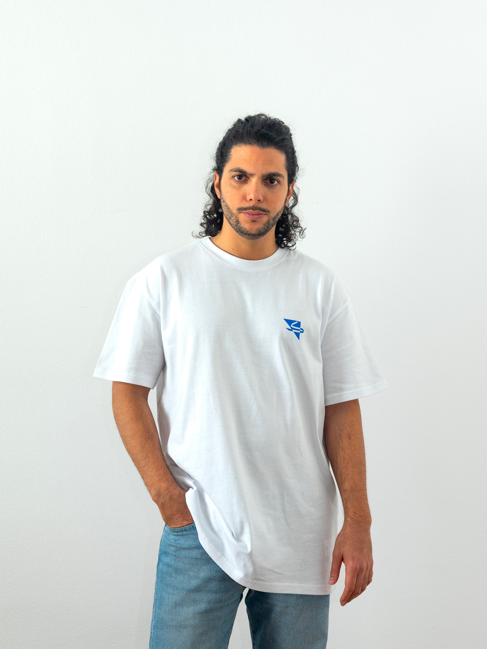 Beautiful arab model wearing a cool and creative over-sized t-shirt for streetwear and everyday lifestyle clothing. It features a simple beautiful logo, which is geometric in design and that has an arabic letter within it.  White t-shirt. Frontside view. Blue print color.