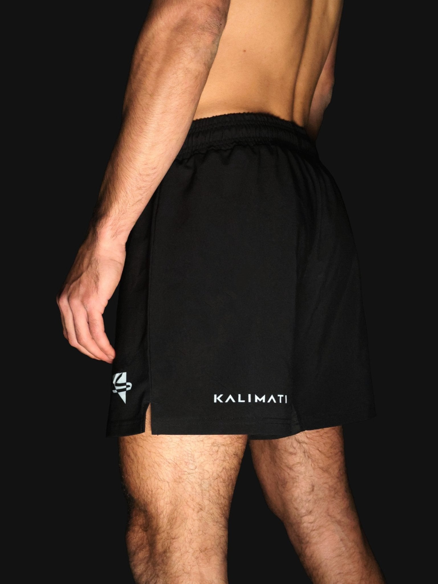 Arab athlete wearing black grappling and fight shorts for mixed martial arts (MMA), jiu-jitsu (Gi or No-Gi), and other combat sports. Comfortable, high-quality, and durable design, featuring arabic brand on the front. Made by athletes, for athletes. Professional design and materials. Back side view.