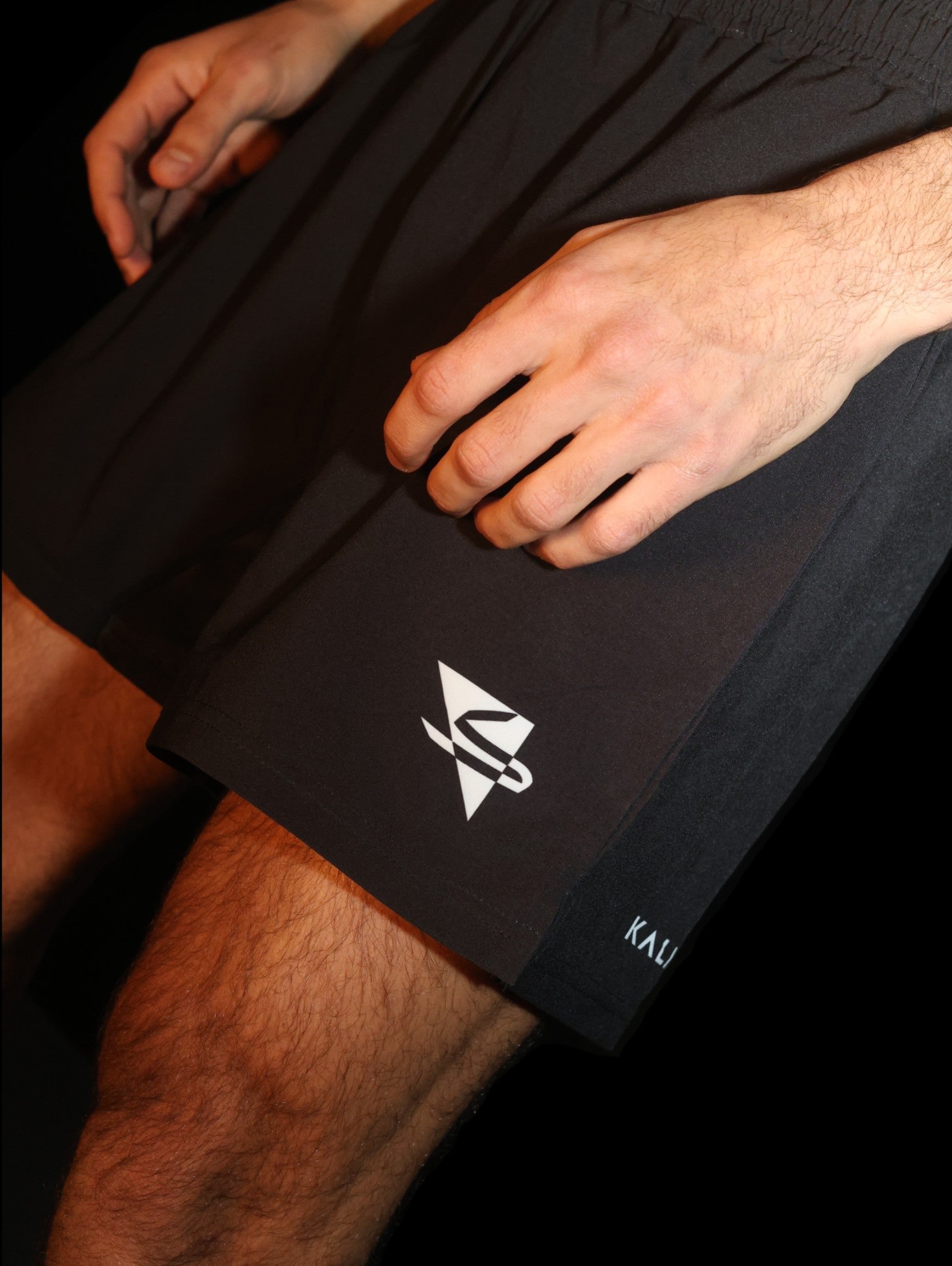 Arab athlete wearing black grappling and fight shorts for mixed martial arts (MMA), jiu-jitsu (Gi or No-Gi), and other combat sports. Comfortable, high-quality, and durable design, featuring arabic brand on the front. Made by athletes, for athletes. Professional design and materials. Front side view.