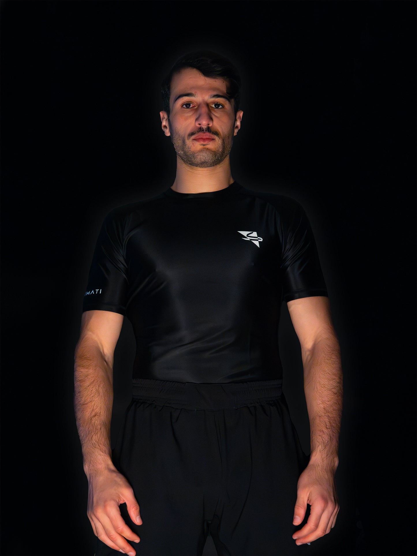 Black rashguard with arabic logo used for training jiu-jitsu and other martial arts (e.g. MMA). Front view. Black and white print color. Wide angle.