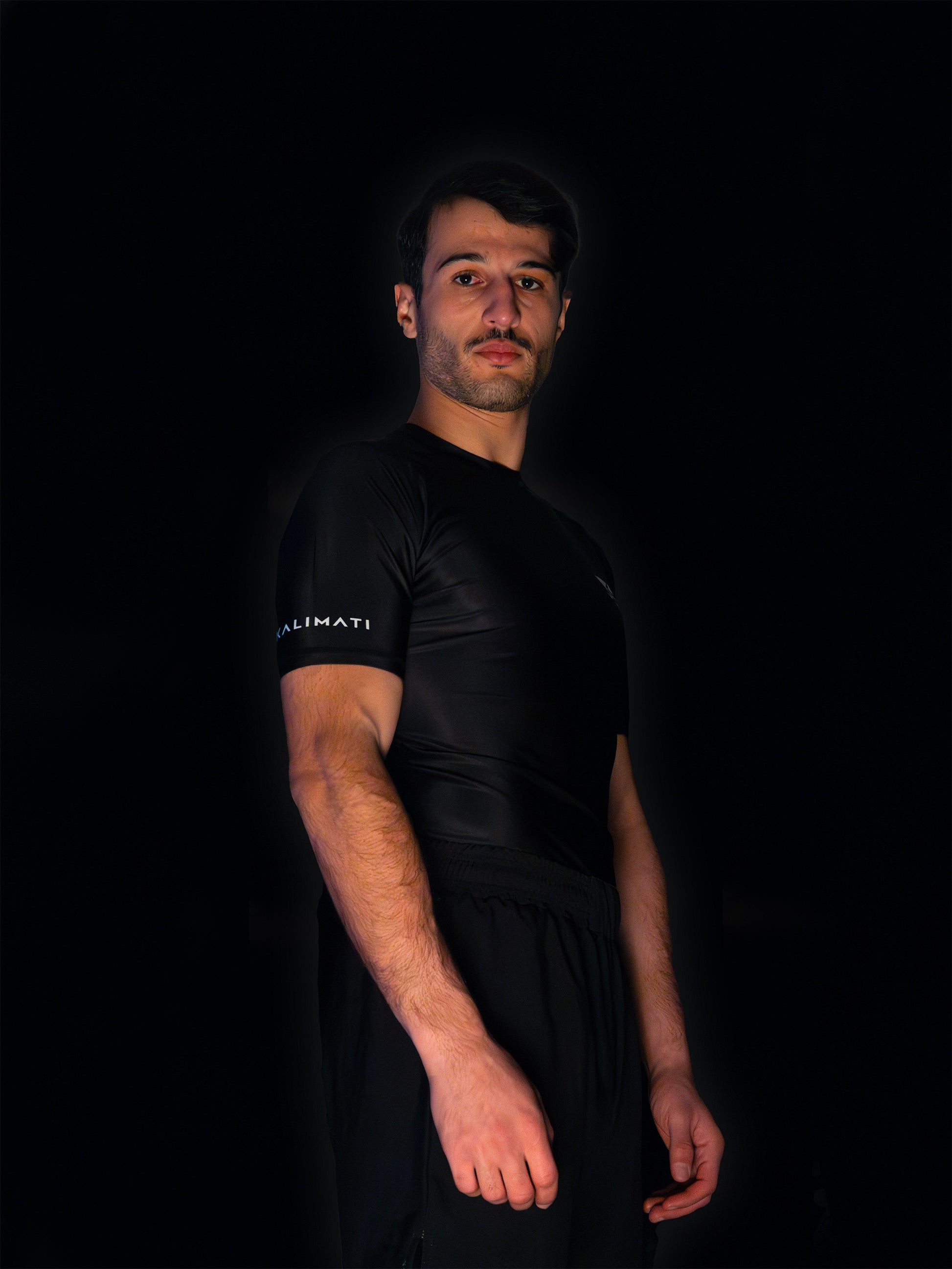 Black rashguard with arabic logo used for training jiu-jitsu and other martial arts (e.g. MMA). Rightside view. Black and white print color.