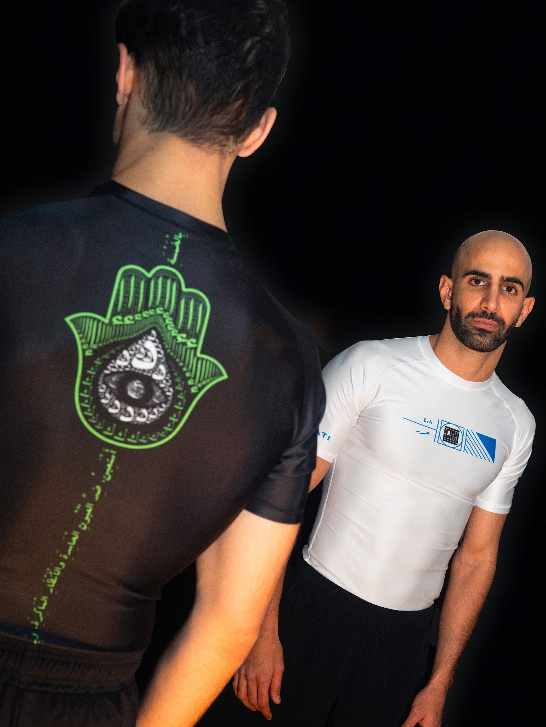 Two arabic fighters and martial artists facing each other. Each is wearing a cool, unique ashguard for jiujitsu and other combat sports. One is wearing white and blue, and the other black and green , with a khamsa symbol.